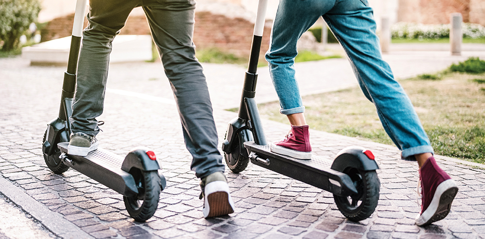 Close up of people couple using electric scooter in city park - Millenial students riding new modern ecological mean of transport - Green eco energy concept with zero emission - Warm sunshine filter