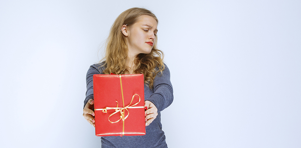 Blonde girl looks dissatisfied and returning her red gift box. High quality photo