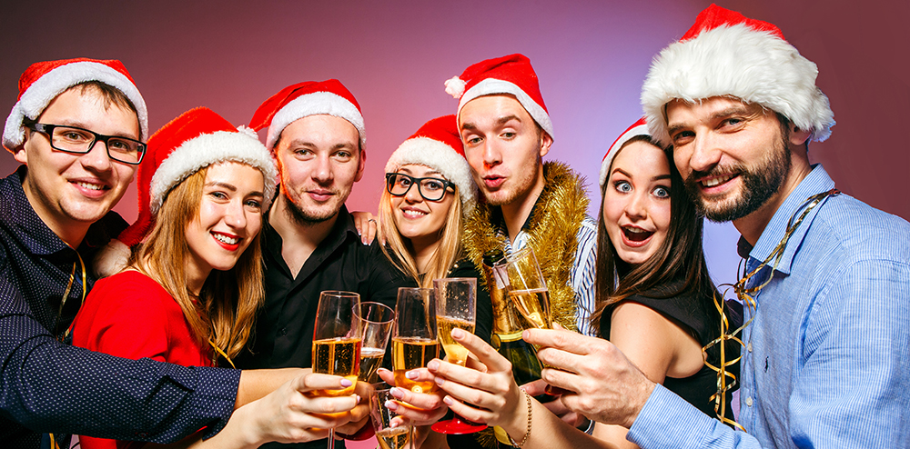 Many young women and men drinking at christmas party on pink studio background