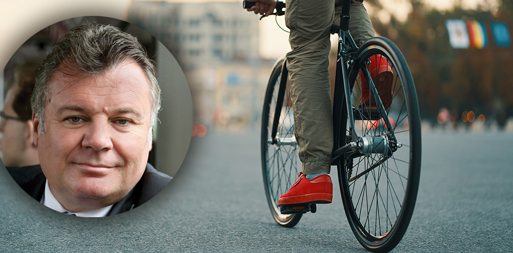 Closeup of casual man legs riding classic bike on city gray road wearing red sneakers and comfy pants. Copy space